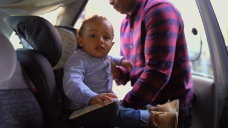 Father-putting-little-boy-into-baby-seat,-fastening-seat-belts
